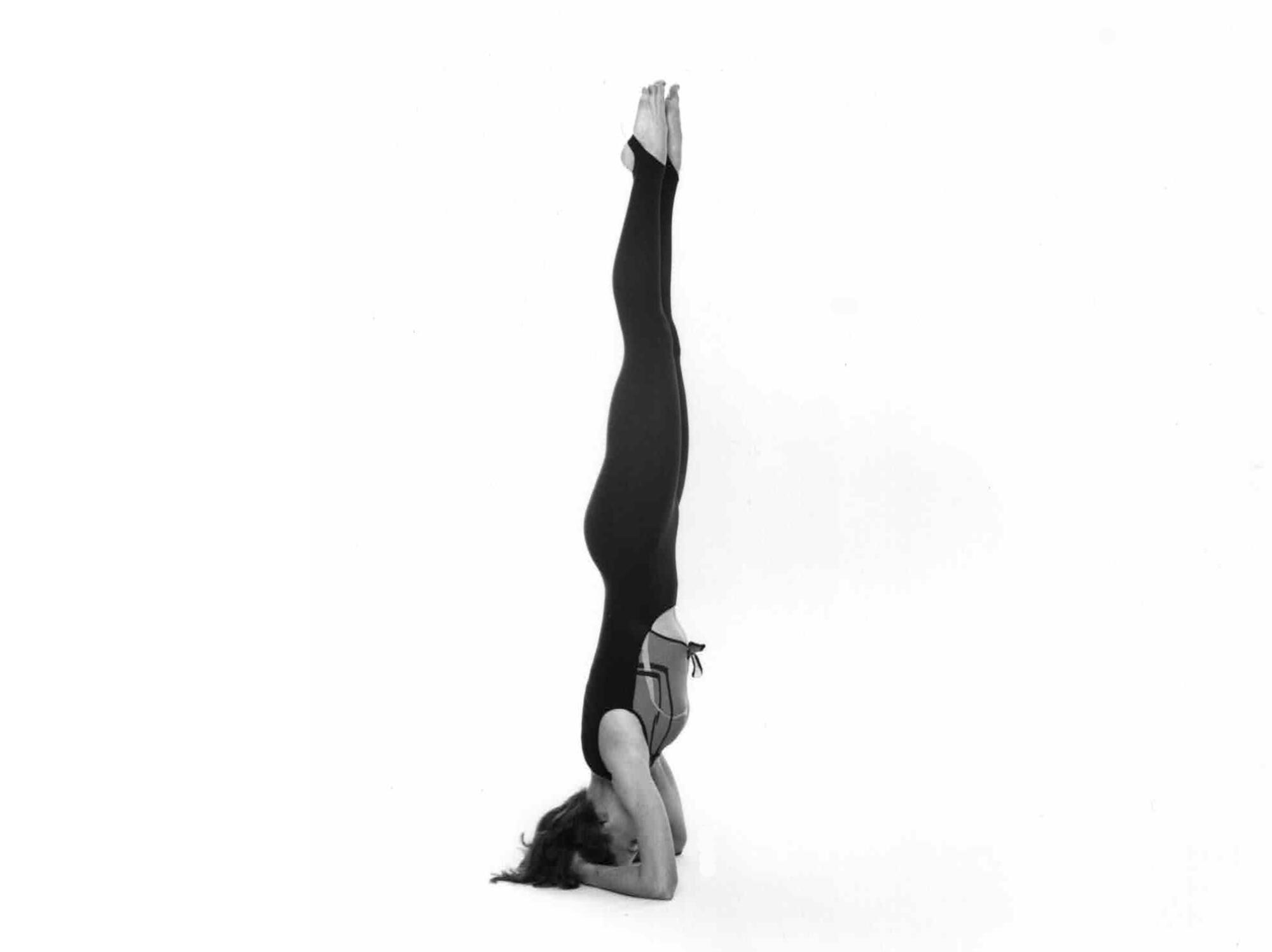 Roxanne Darling Headstand 1983 photo of roxanne darling in a black unitard doing a headstand against a white background; photo credit fernand fonssagrives